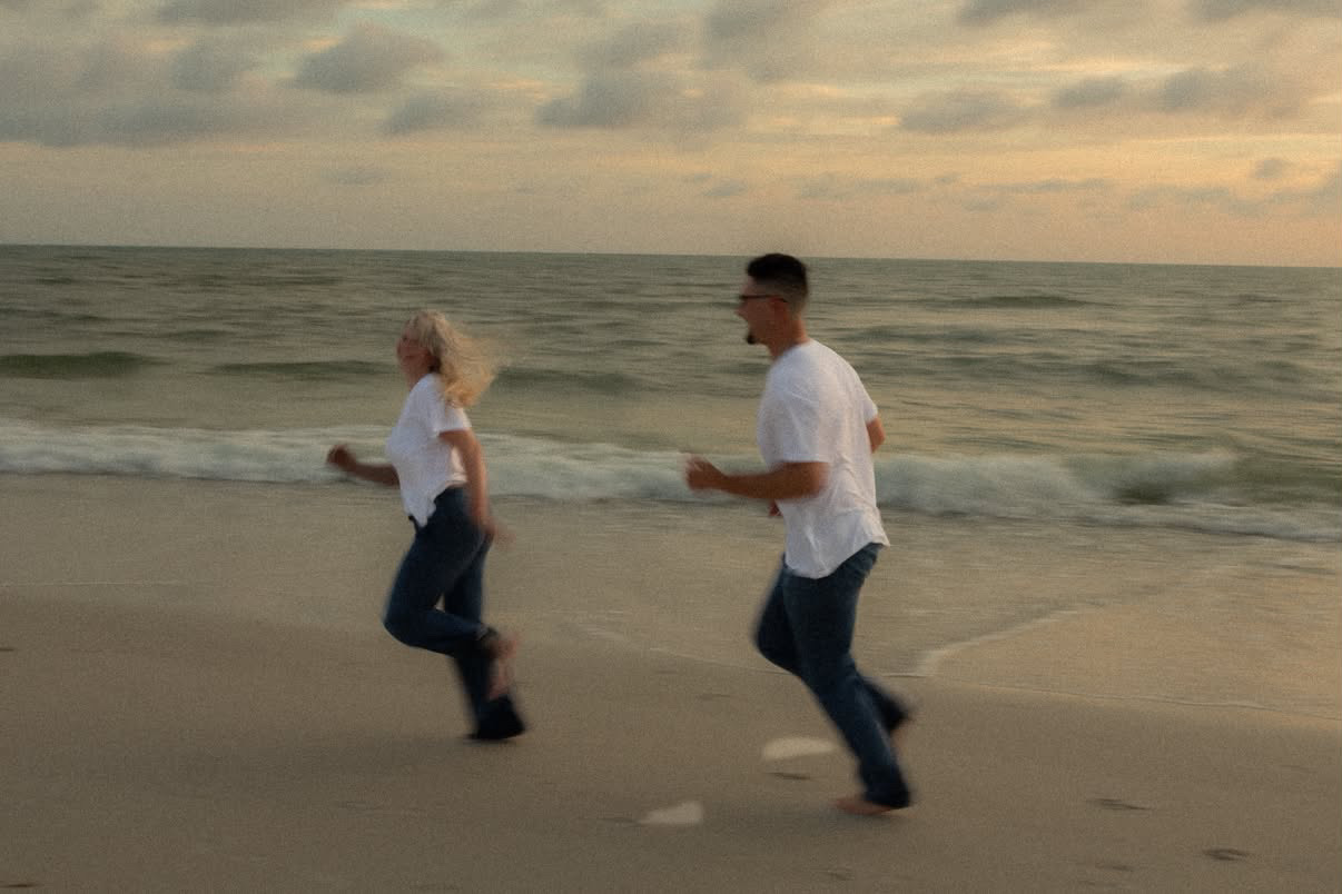 Couple running along the beach at sunset